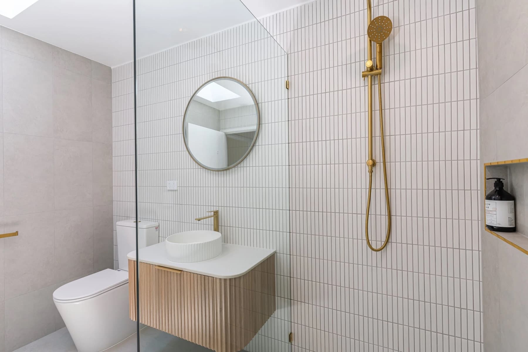A JAYMA Projects bathroom renovation in Cannon Hill, Brisbane, with warm stone tile, brass tapware and soft daylight.