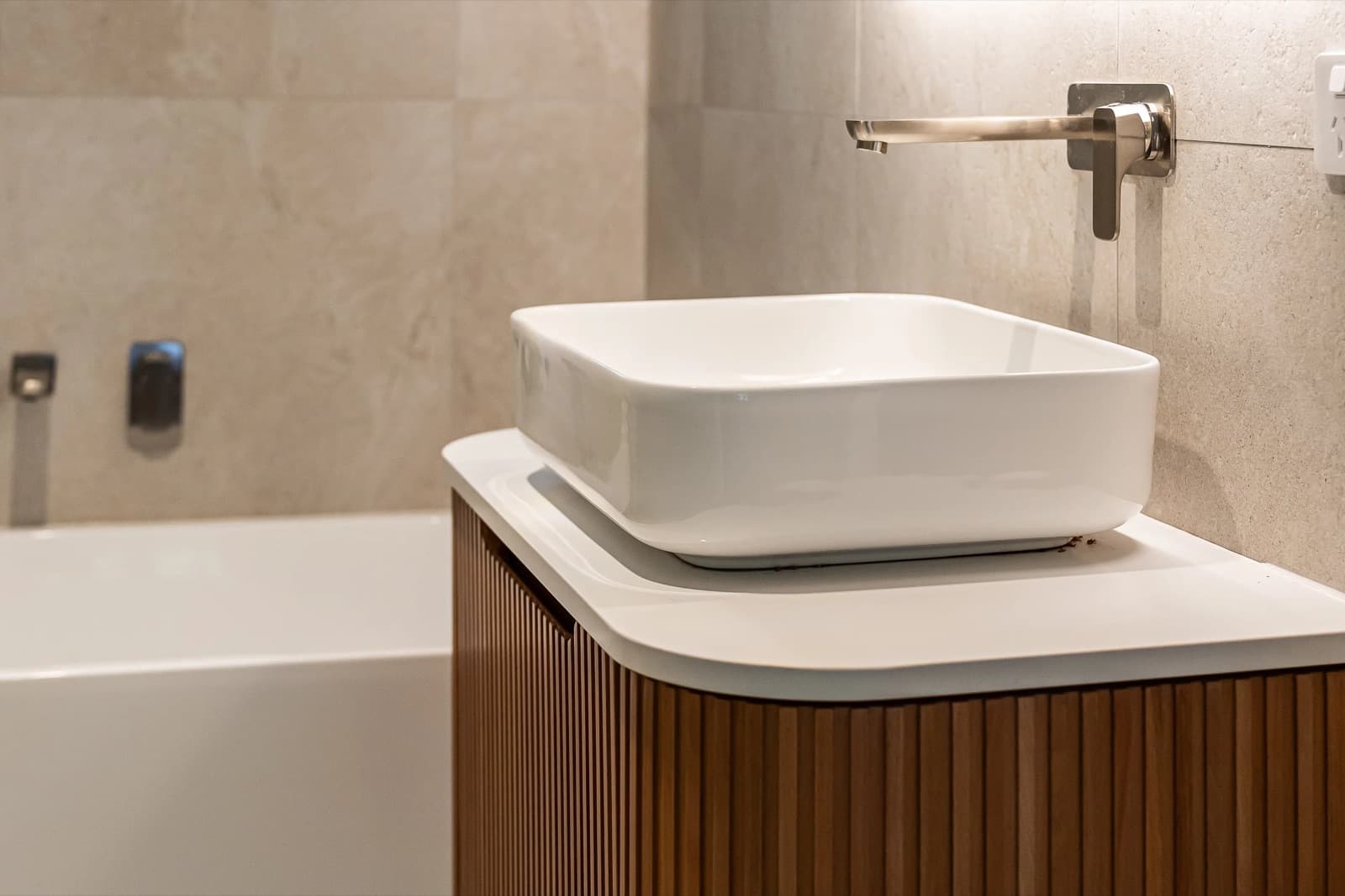 A serene, finished JAYMA bathroom renovation with soft daylight, stone-look tiling and styled greenery.