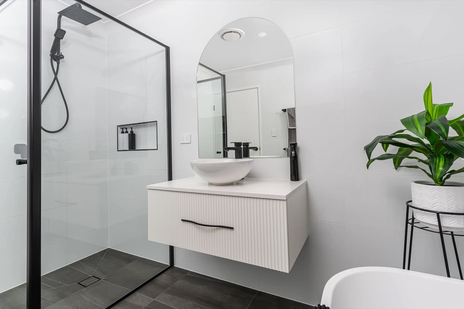 A finished JAYMA bathroom with bright tile, matte-black tapware, fluted vanity and a vessel basin.