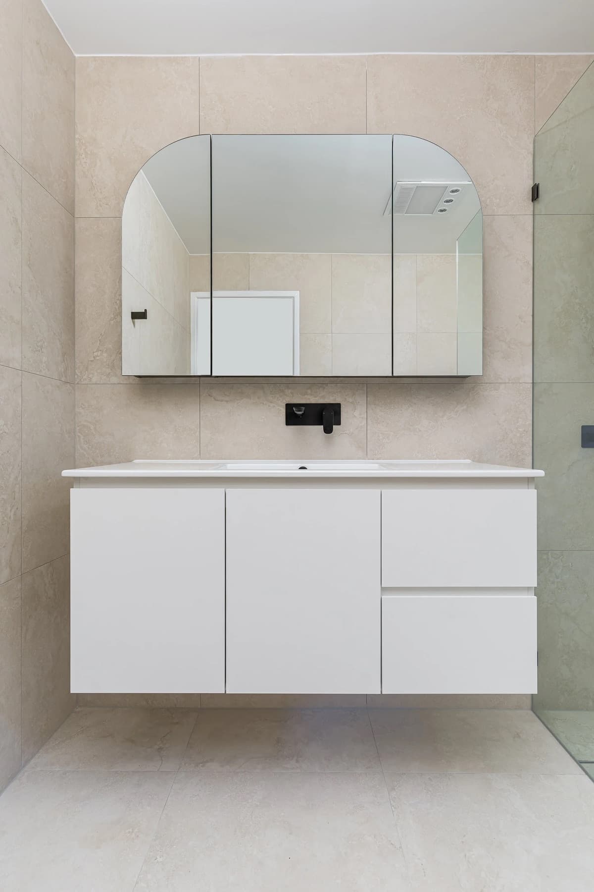 Renovated McDowall bathroom with matte-black fixtures, soft beige wall tiles and a rectangular soaking tub.