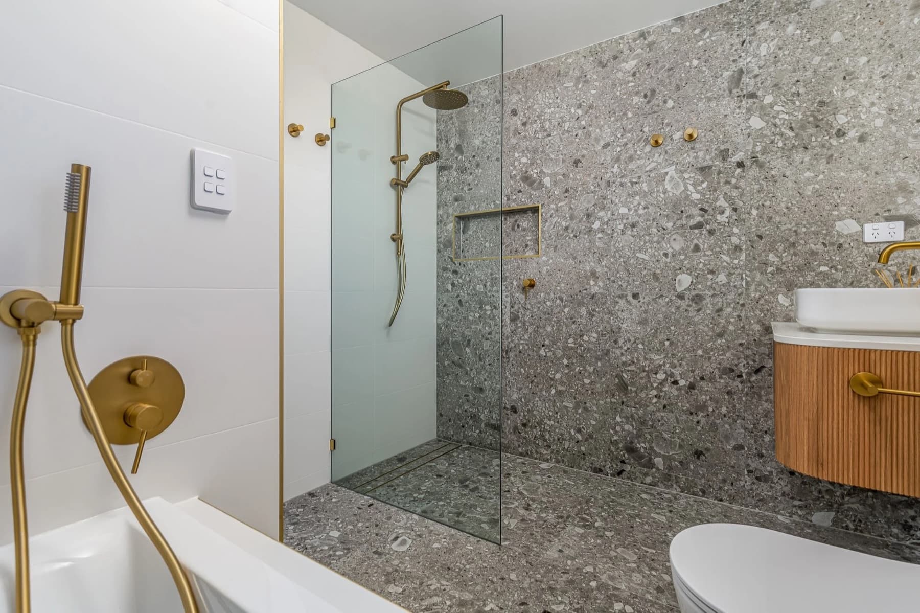 Renovated Bray Park bathroom with terrazzo tiles, brass fixtures and a sleek timber vanity.